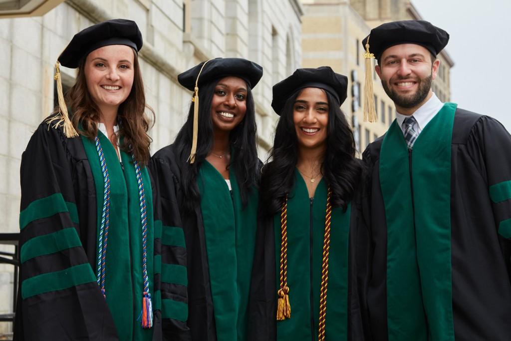 四名C O M学生在毕业典礼前身着绿黑相间的校服