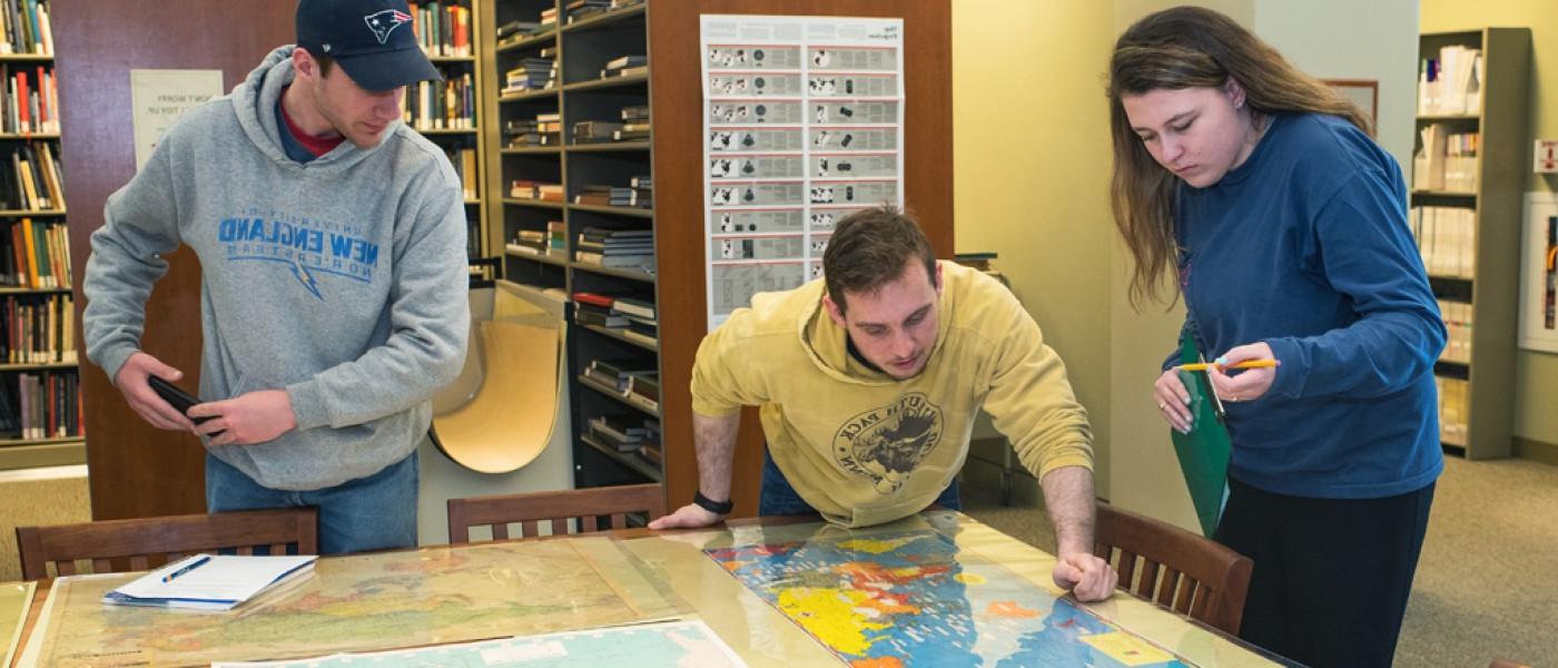 三个东北大学文科生在图书馆研究一幅大地图